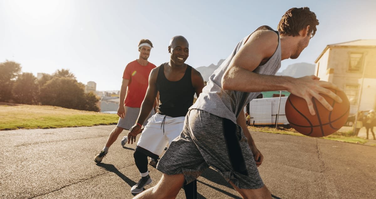 Arthroscopic Knee Surgery Recovery: A Delray Beach Sports Medicine Guide Active men playing basketball outdoors, representing a return to sport after arthroscopic knee surgery recovery at Tyrance Orthopedics in Delray Beach.