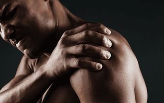 Man grimacing while gripping his painful shoulder, a sign of a rotator cuff injury treated with PRP therapy at Tyrance Orthopedics in Delray Beach.