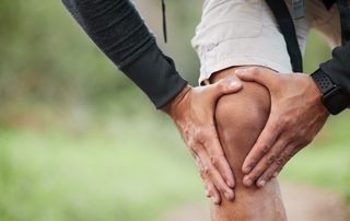 Hiker gripping a painful knee on a trail, the kind of injury that leads to ACL reconstruction and the recovery that follows.