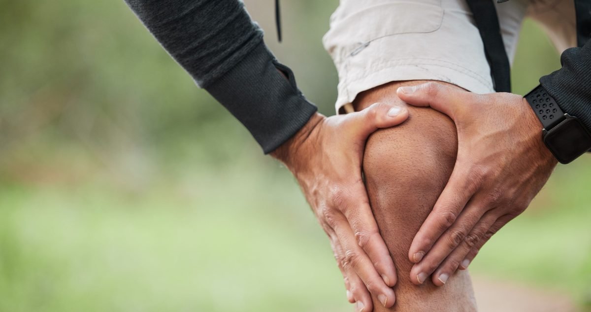 ACL Reconstruction Recovery: What to Expect After Surgery Hiker gripping a painful knee on a trail, the kind of injury that leads to ACL reconstruction and the recovery that follows.