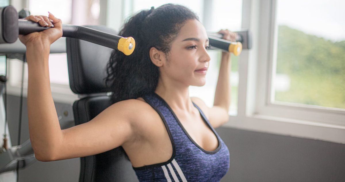 PRP for Shoulder Pain Woman working a shoulder press machine in a gym, the overhead strength PRP treatment is meant to give back.