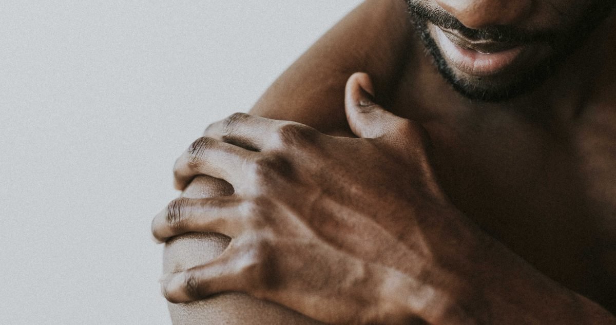 Shoulder Bursitis Symptoms Man holding his sore outer shoulder, the area of the subacromial bursa where shoulder bursitis symptoms appear.